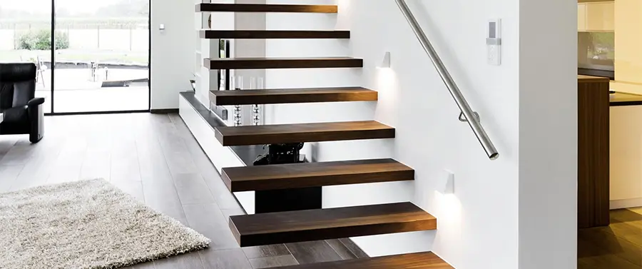 Ein moderner Treppenbau mit schwebenden Holzstufen, Metallhandlauf und eingebetteter Wandbeleuchtung in einer modernen Wohneinrichtung.