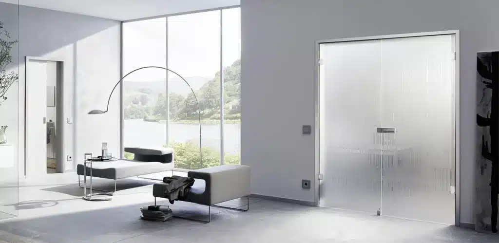 Ein modernes Wohnzimmer mit großen Fenstern und Glastüren mit Blick auf einen See, minimalistischen Möbeln und Dekor sowie einer markanten Bogen-Stehlampe.