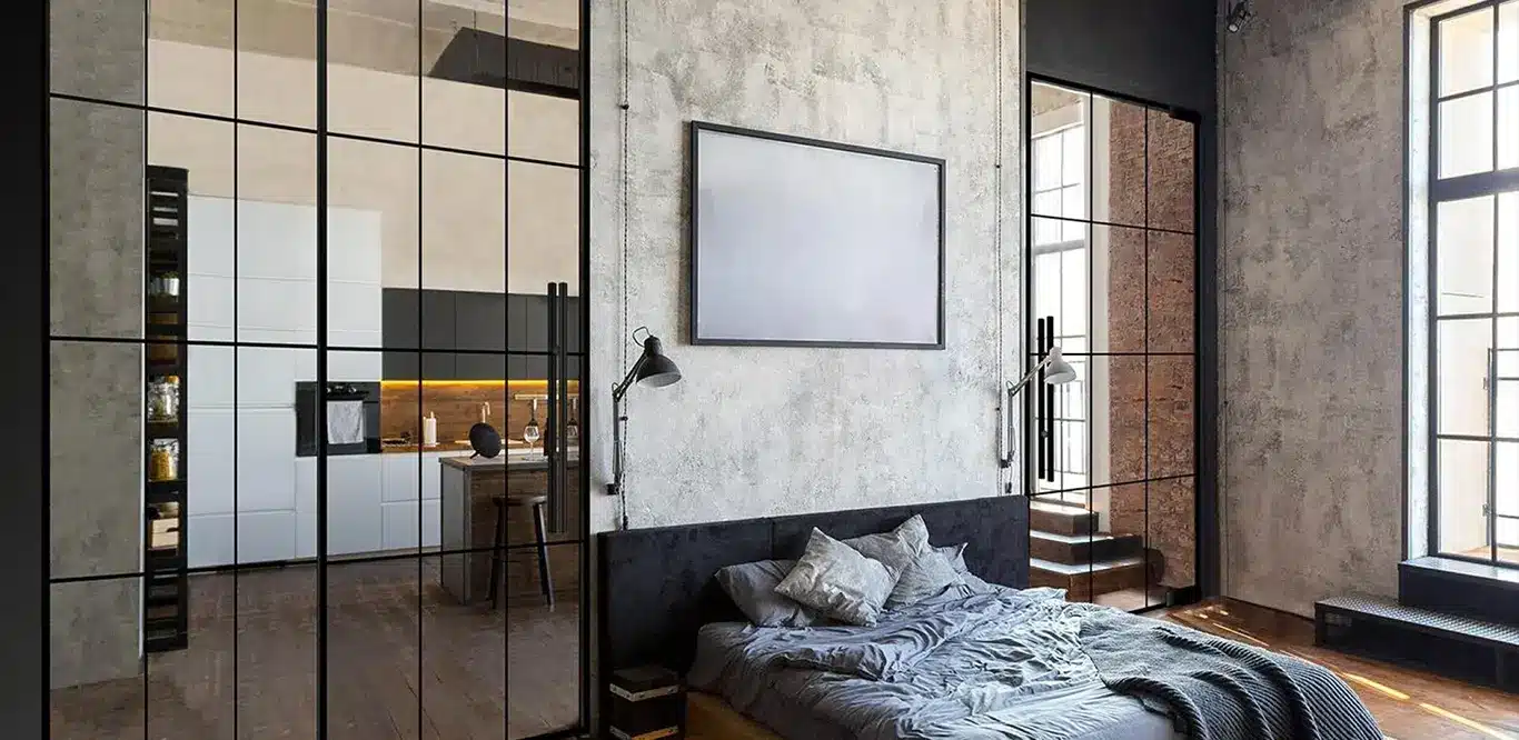 Modernes Schlafzimmer im Industriestil mit monochromatischem Farbschema, Lofttüren und einer Glaswand mit Metallrahmen, die das Schlafzimmer vom angrenzenden Raum trennt, Sichtbetonwänden und einem großen Bett mit