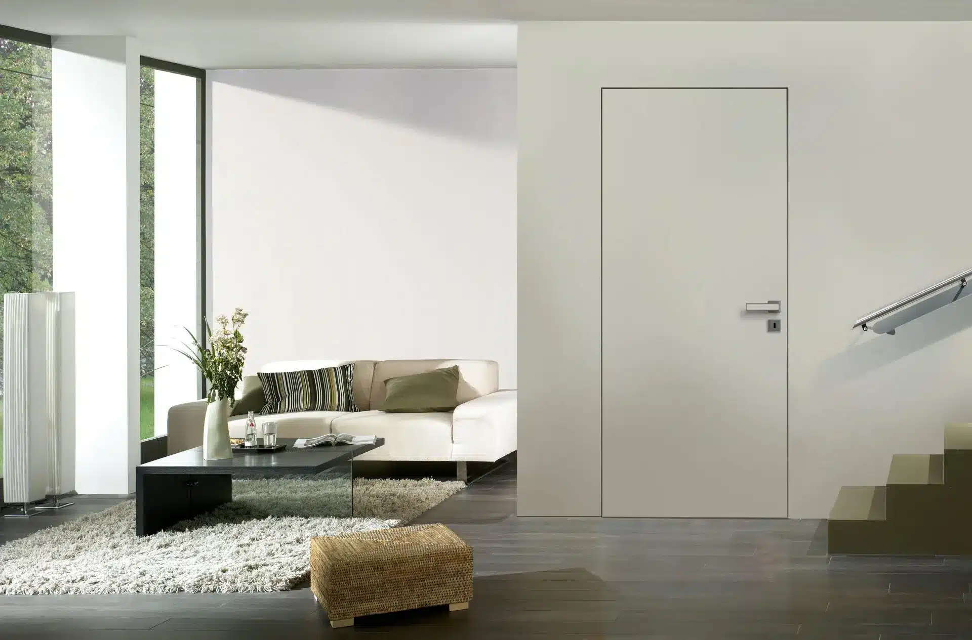 Ein modernes Wohnzimmer mit einem weißen Sofa, einem dunklen Couchtisch, einem zotteligen Teppich und minimalistischem Dekor mit großen Fenstern, Weißlacktüren und einer Treppe mit Glasbalkon