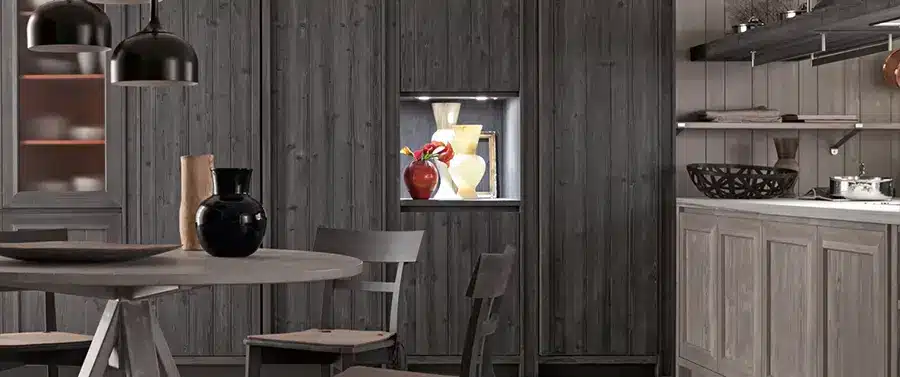 Ein modernes Küchenstil-Interieur mit dunklen Holzwänden und einem kleinen, eingelassenen Regal mit einer Vase mit Blumen und Früchten.