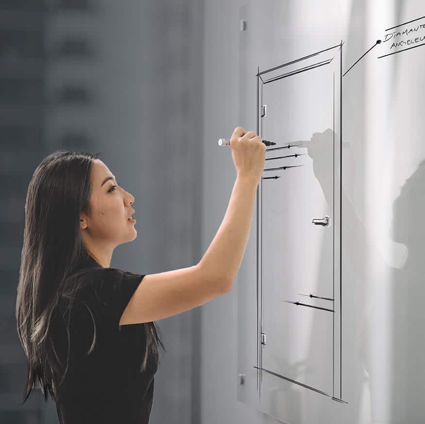 Eine Frau zeichnet mit einem Marker ein Diagramm auf ein Whiteboard, beleuchtet von der Licht-Harmonie.