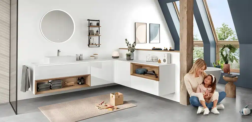Eine Mutter und ein Kind sitzen auf dem Boden einer modernen Wohnzimmereinrichtung mit minimalistischem Design und interagieren liebevoll in der Nähe eines Spielbereichs mit Spielzeug.