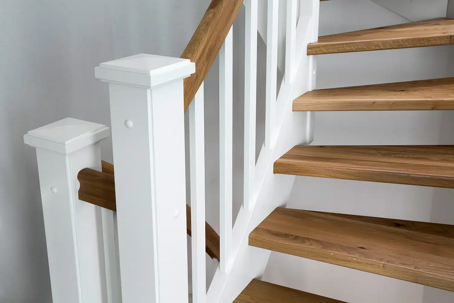 Eine moderne Wangentreppe mit Holzstufen und einer weißen Balustrade.