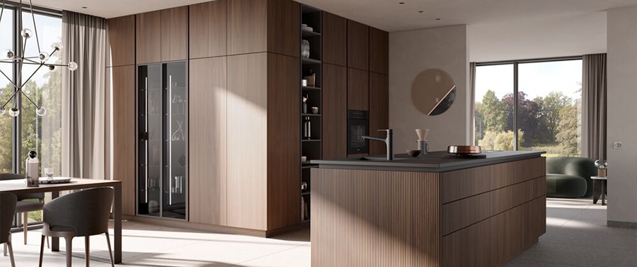 Modernes Interieur im Küchenstil mit Holzoberflächen, zentraler Kücheninsel, Einbaugeräten und einem großen Fenster mit Blick ins Grüne.